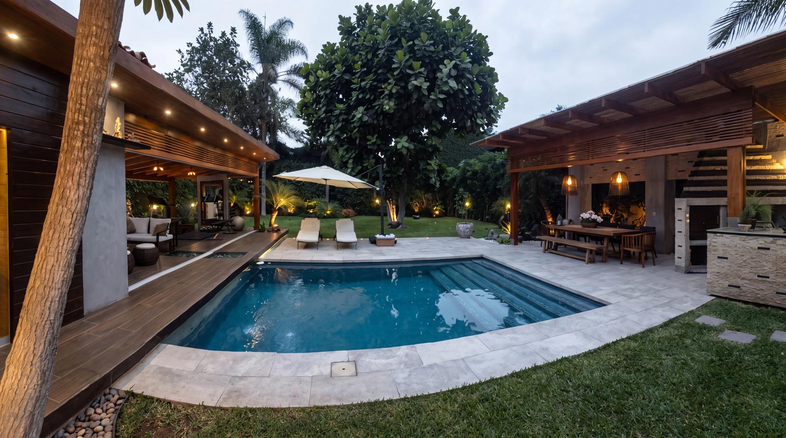 Terraza Oasis: la pérgola de madera, la sala exterior y la piscina al caer la tarde